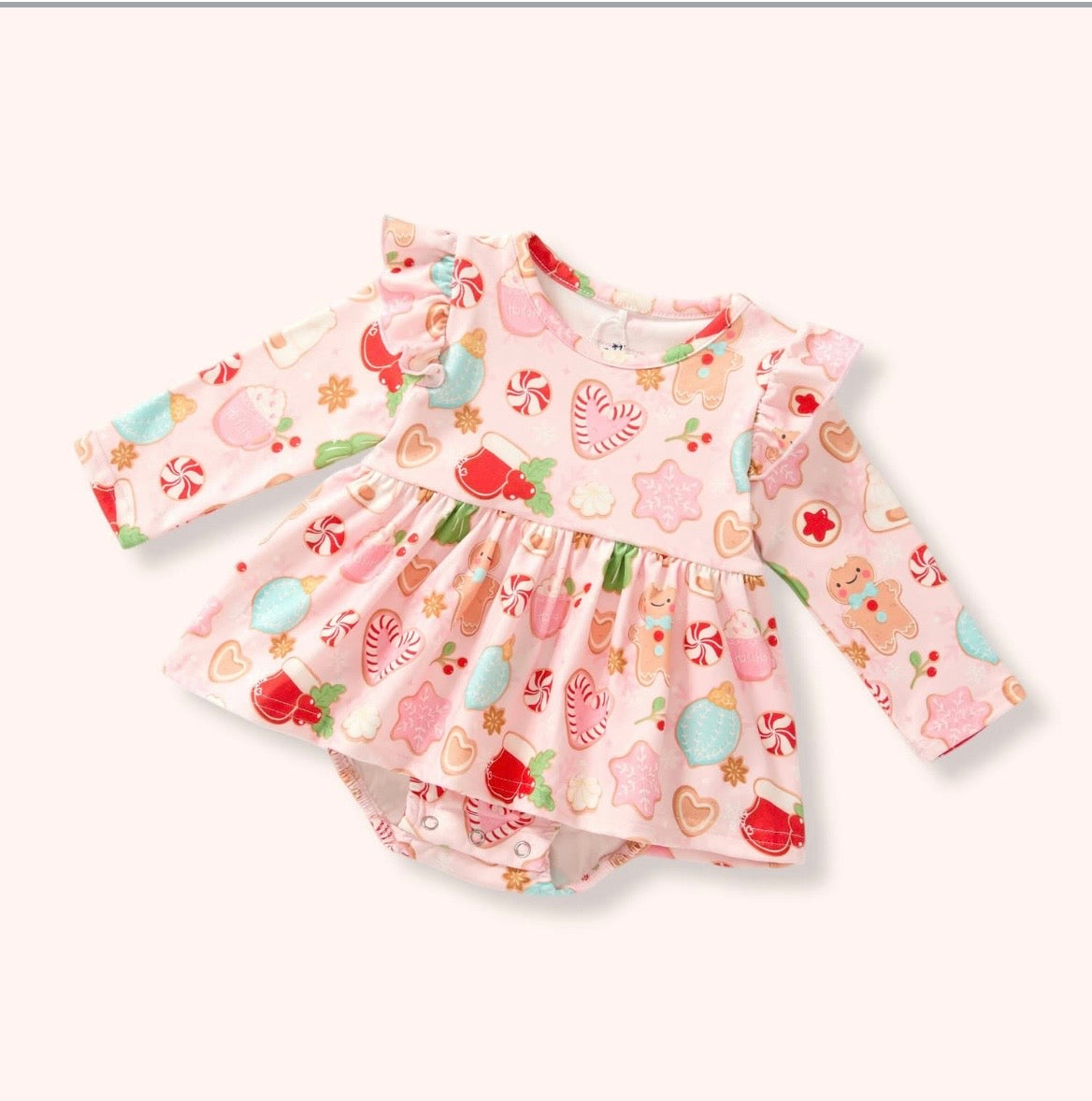 Light pink Christmas Cookies Romper with holiday cookie and candy print, long sleeves, ruffled shoulders, skirt overlay, and bottom snaps.